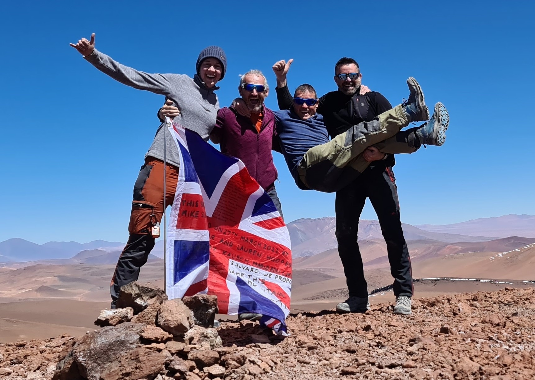 Equipo con la bandera de la Unión en la cima de Solan Peak